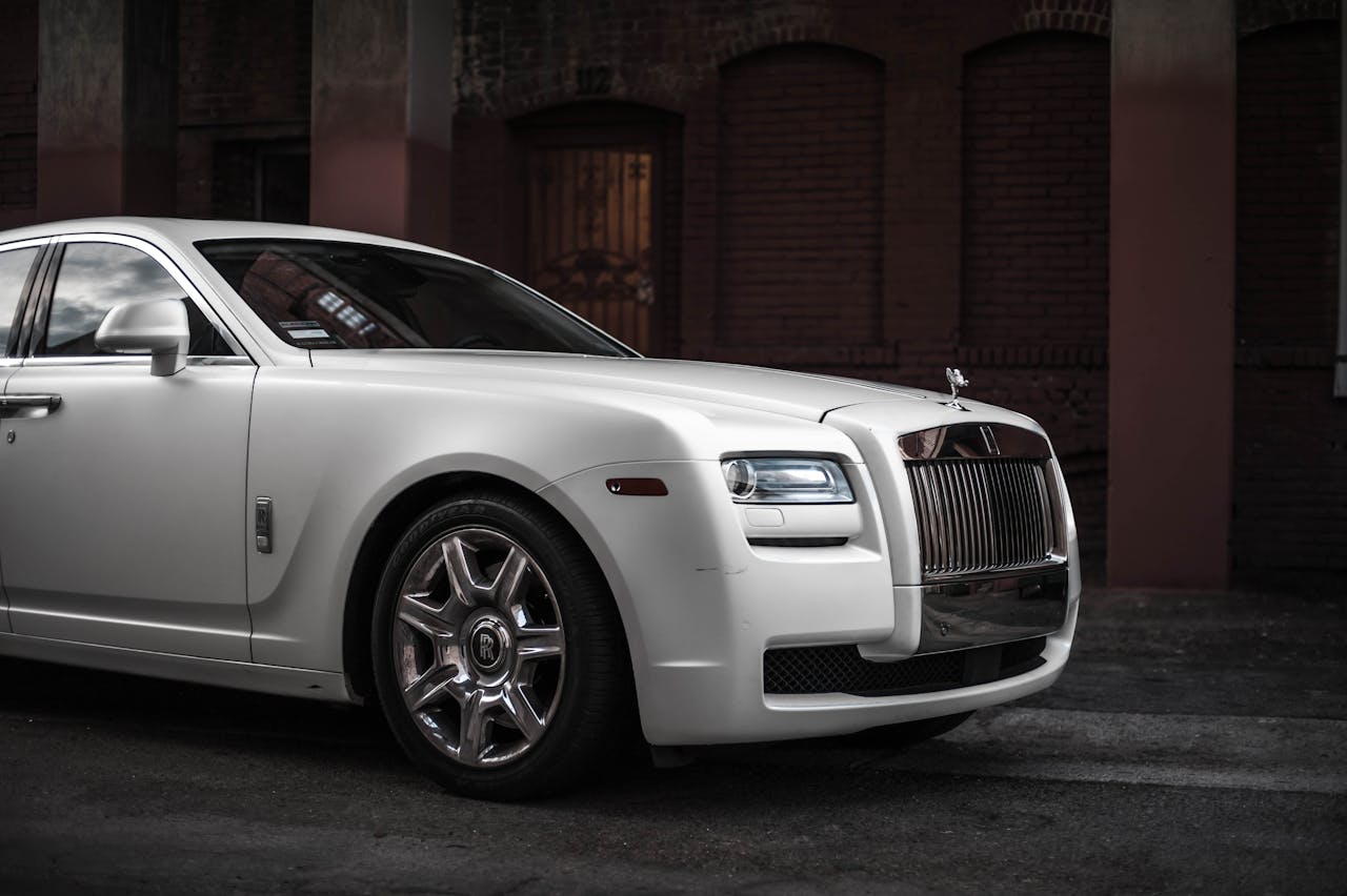 about-01 Elegant white Rolls Royce Ghost parked in a stylish urban backdrop, showcasing luxury and design.